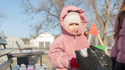 Grandfather playing with her granddaughters on the playground in the park in winter