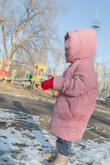 little girl playing on the playground on a winter day
