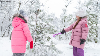 Two little girls playing in a snowy park in winter