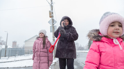 Grandmother with grandchildren in warm clothes playing outdoors in winter park, enjoying snowy...