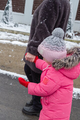 Grandmother walks with her granddaughter along a snowy street in winter