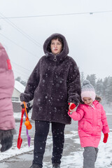 Grandmother and girls walk along a snowy street in winter