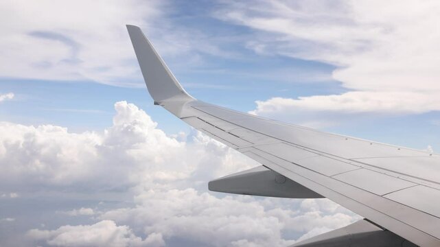 Commercial flight view over the wing with bright puffy clouds