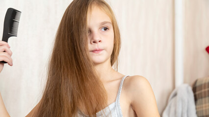 Naklejka premium 8 years old girl brushing her long hair in her room in the morning