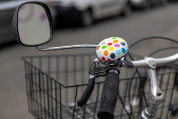 Colorful bicycle bell and mirror on a parked bike near cars in an urban setting during day time