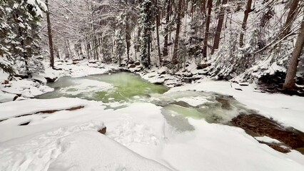 Frozen mountain river with a waterfall in a winter snowy forest