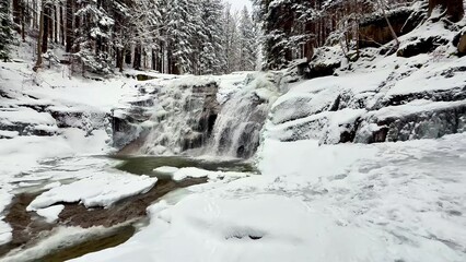 Obraz premium A frozen mountain river with a waterfall in a winter forest