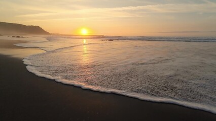 Obraz premium Witness the Beautiful Sunset Over the Tranquil Waves of the Beach That Captivates All