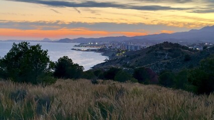 A serene and beautiful coastal sunset gracefully painted over the rolling hills and vast ocean