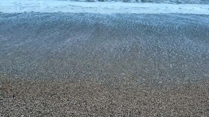 Enjoying the soothing and serene experience of beach waves gently lapping at pebbles during dusk