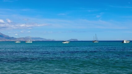 Fototapeta premium A Serene Coastal View Featuring Boats Floating on Clear Blue Water Surface in the Horizon