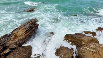 The beautiful and serene coastal waves are crashing rhythmically on the rocky shoreline