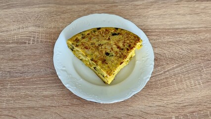 A delicious, colorful slice of Spanish Tortilla beautifully presented on a plate ready to enjoy
