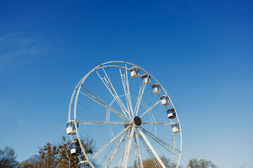 Fototapeta premium A large Ferris wheel against a blue sky. Cabins on the Ferris wheel.