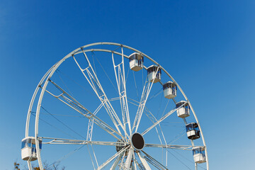 A large Ferris wheel against a blue sky. Cabins on the Ferris wheel.