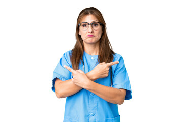 Middle age nurse woman over isolated background pointing to the laterals having doubts
