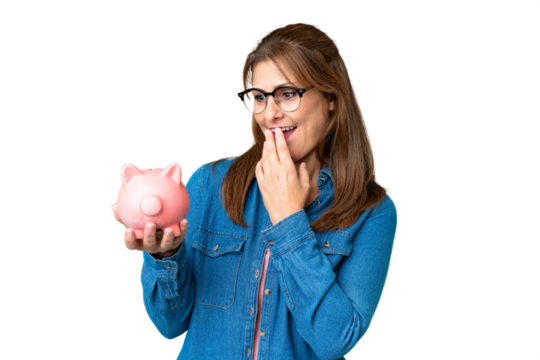 Middle age caucasian woman holding a piggybank over isolated background with surprise and shocked facial expression