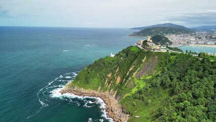 Aerial view of the stunning coastline and green hills by a vibrant seaside city
