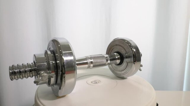 Top view. Vinyl dumbbell yellow 1 kg weight, on a rotary table, sports dumbbell spins. On a colorful stylish background