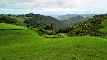 Enjoy the breathtaking views of scenic green hills and lush valleys beneath a cloudy sky