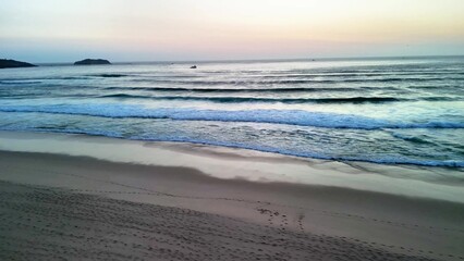 Experience the stunning beauty of serene beach waves gently lapping at the shore during dusk
