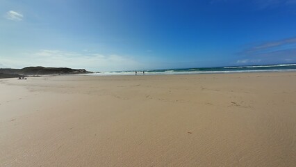 A picturesque beach scene featuring a vibrant blue sky above, with calm, gentle waves all around