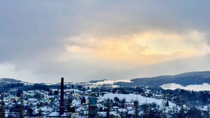 Obraz premium A Serene Winter Landscape Featuring a Smokestack, SnowCovered Hills, and a Tranquil Atmosphere