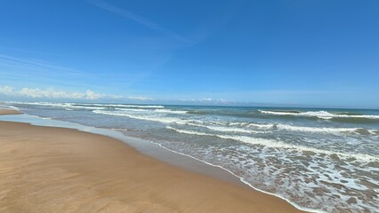 Obraz premium A Serene Beach Landscape Featuring Gentle Waves Under a Clear Blue Sky in Tranquility