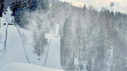 A beautiful snowy ski jump and an enchanting winter wonderland landscape can be seen