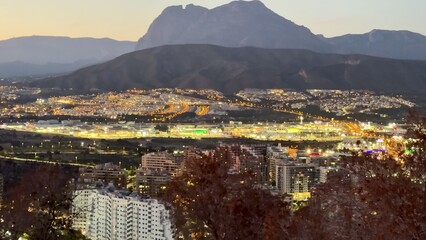 Admire the stunning city lights at dusk with a magnificent mountain backdrop for a captivating view © Vladimir