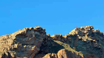 The stunning Rocky Peaks rise dramatically against a clear blue sky, creating a breathtaking view