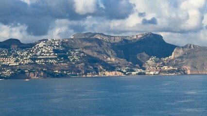 A breathtaking scenic coastal view featuring majestic mountains and fluffy clouds in the sky