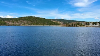 A stunning lake view is framed by vibrant greenery and expansive blue skies above