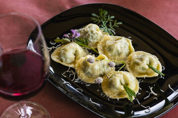 A white plate features beautifully arranged Cjarsons, a traditional pasta dish from Carnia in Friuli Venezia Giulia, garnished with grated cheese and spices.