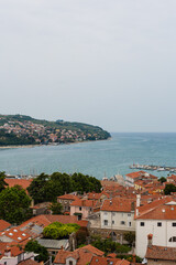 A scenic view of the Adriatic Sea and the coastline from Koper, Slovenia, showcasing the town's red-tiled roofs and the calm waters with a harbor.