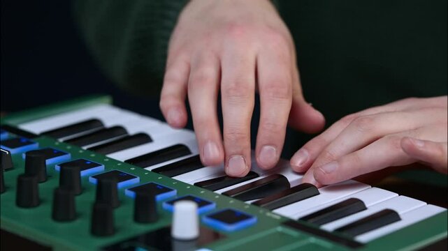 Close-up of male hands playing a mint green dual-action MIDI keyboard.