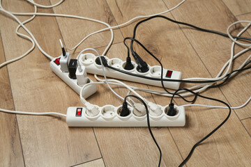 Extension power boards overloaded with plugs on wooden floor