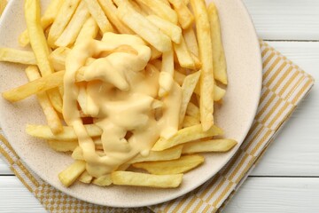 French fries with cheese sauce on white wooden table, top view