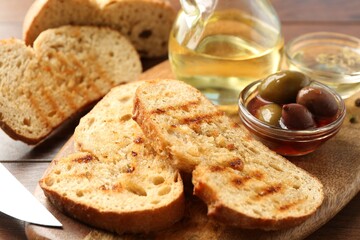 Toasted bread with oil and olives on table, closeup