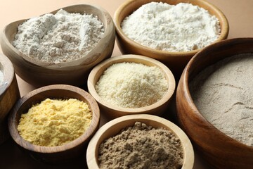 Different types of flour on light brown table, closeup