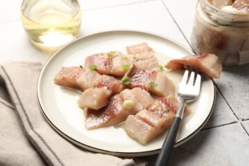 Pieces of delicious herring with green onions on tiled table, closeup