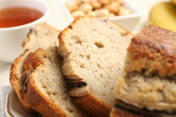 Cut banana bread with nuts and tea on table, closeup