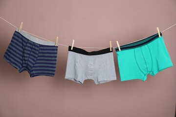 Comfortable men's underwear on clothes line against light brown background