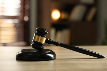 Judge's gavel on wooden table against blurred background, closeup