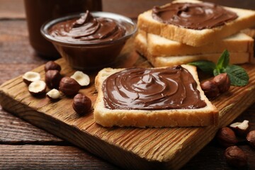 Toasts with chocolate hazelnut spread, nuts and mint on wooden table, closeup