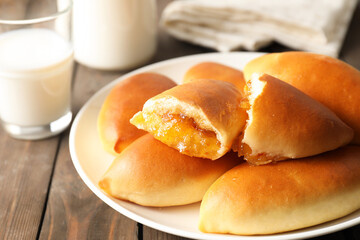 Tasty baked patties with orange jam on wooden table, closeup