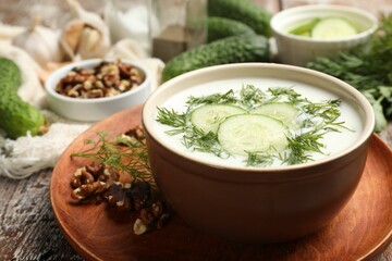 Tasty cucumber soup with dill and nuts on wooden table, closeup