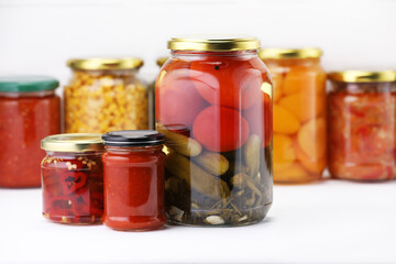 Many jars with different pickled products on white wooden table