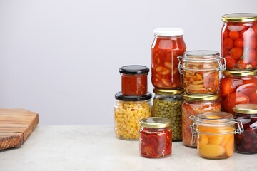 Many jars with different pickled products on light grey table, space for text