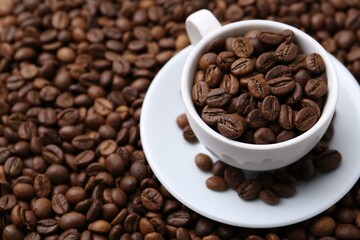 Cup and saucer on coffee beans, closeup. Space for text